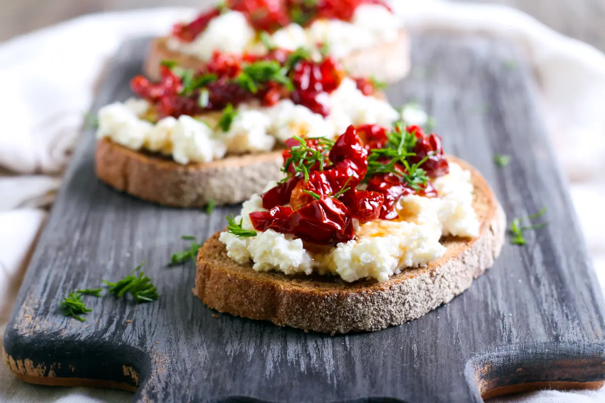 tomaten_getrocknet_brot_ricotta_olivenoel_holzbrett tomaten_getrocknet_brot_ricotta_olivenoel_holzbrett