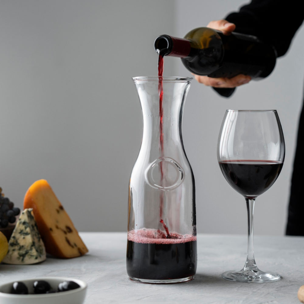 Mann gießt Wein in Karaffe