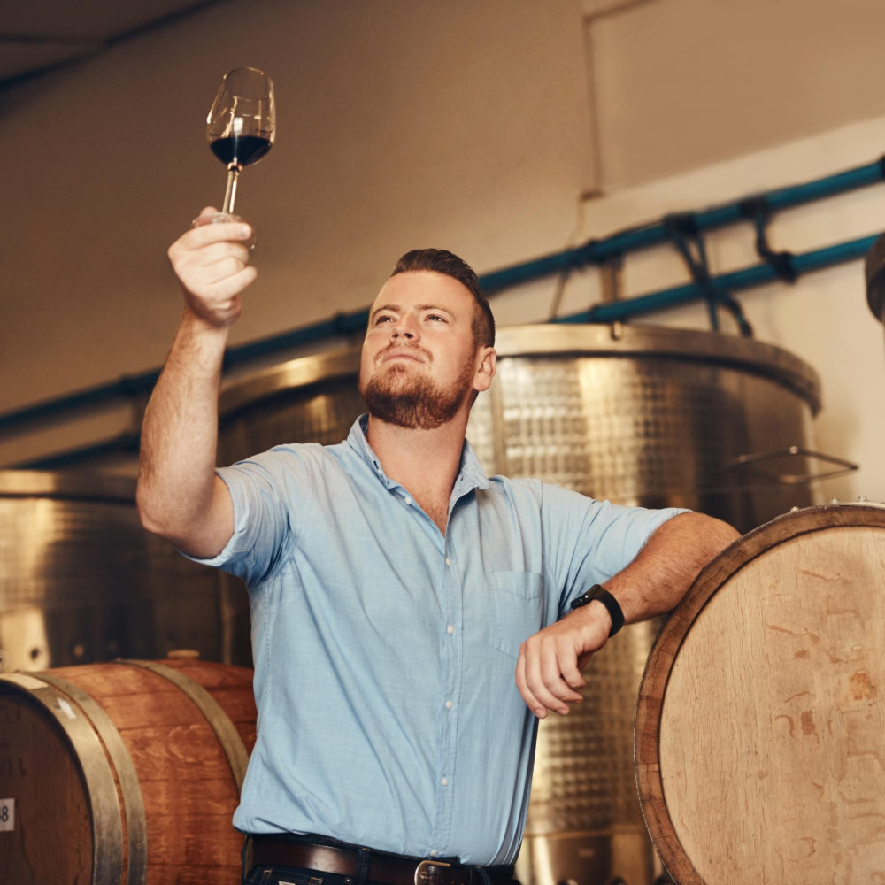 Glas stolz und denkend mit dem Mann in einem Weinkeller
