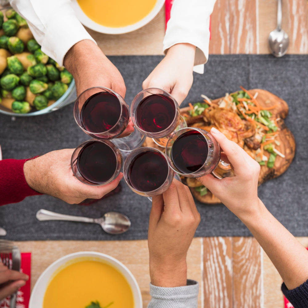 Menschen klingeln mit Weingläsern über einem festlichen Tisch