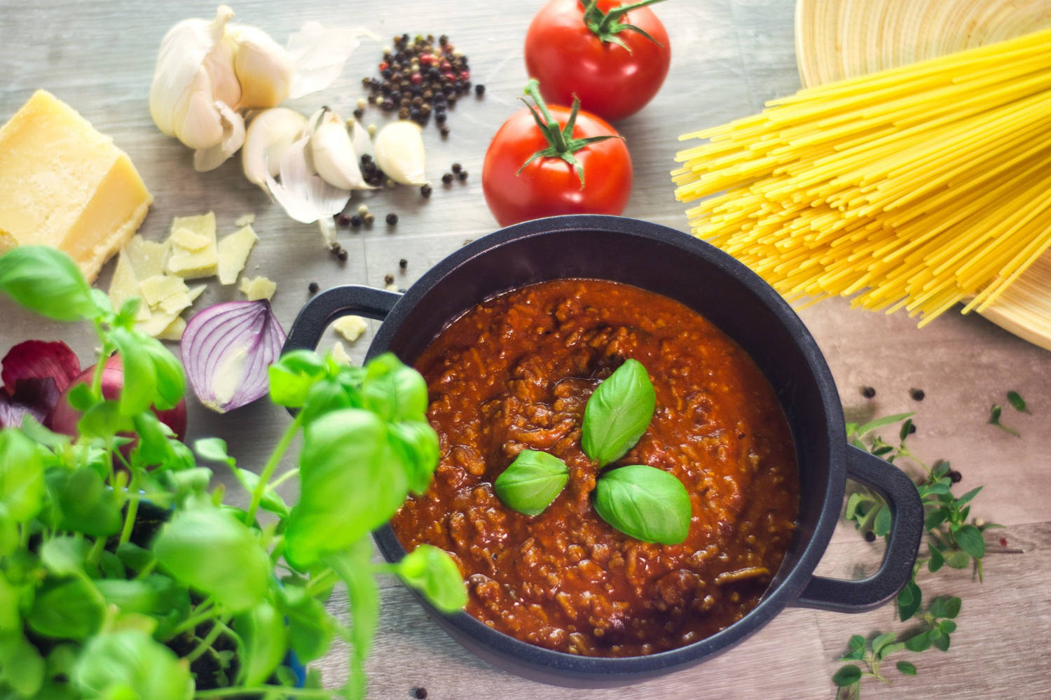 Schwarzer Topf Kochsauce Bolognese mit Zutaten auf einem Holztisc